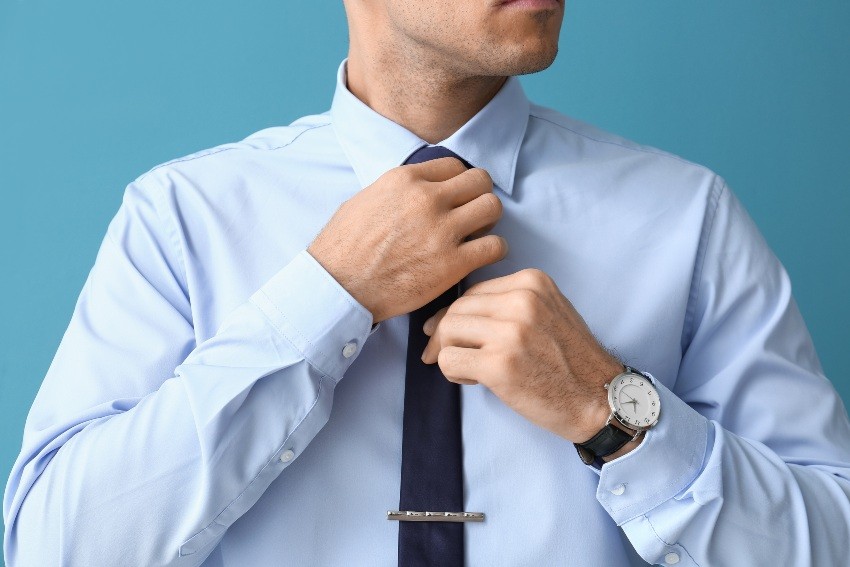 Beim Business Formal Kleidungsstil werden Professionalität und Seriosität auch über die Kleidung kommuniziert Mann-richtet-seine-Krawatte