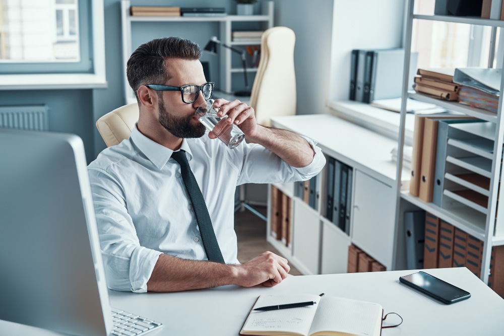 Mann-mit-Hemd-Wasser-trinken-im-Büro