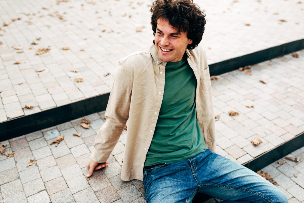 Beige lässt sich durchaus mit kräftigeren Farben wie Grün kombinieren Junger-Mann-mit-Hemd-und-Jeans
